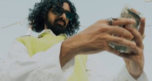 A fashionable man wearing sunglasses counts money outdoors on a sunny day.