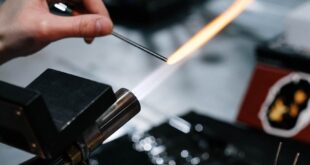 Detailed shot of artisan using torch and tools for metalwork in workshop.