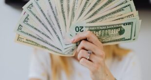 A person holding a fan of US dollar bills, symbolizing wealth and financial success.