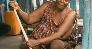 Woman cooking traditionally at a Kumasi market, showcasing Ghanaian culture.