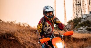 Motocross rider navigating a rocky path in Gündoğdu, Bursa at sunset, surrounded by communication towers.