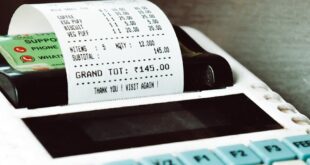 Close-up shot of a cash register printing a receipt with a card nearby, in a retail store.