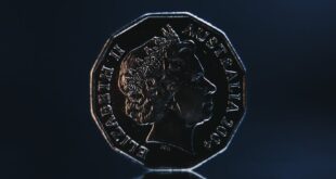 Close-up of an Australian coin reflecting against a dark blue background, highlighting its detailed features.