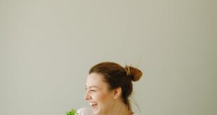 Cheerful woman holding pots of plants, promoting eco-friendly lifestyle indoors.