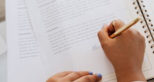 Woman signing a contract with a gold pen, focus on hands and document.