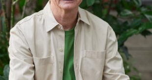 Elderly man enjoying remote work on a laptop in a garden setting.