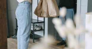 A woman receives a delivery package from a courier at her doorstep inside a modern home.