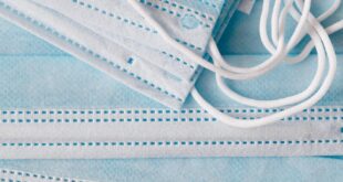 Top view of one use light blue medical respiratory protective face masks placed on top of each other in disorder