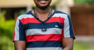 Outdoor portrait of a smiling man in a striped shirt in Obuasi, Ghana.
