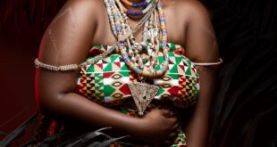 Smiling African woman wearing traditional attire and jewelry, conveying joy and confidence.