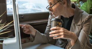 Senior woman in modern home office with coffee, concentrating on computer work.