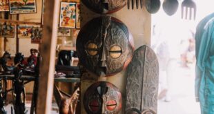 A variety of traditional African masks and souvenirs displayed in an open-air market setting.