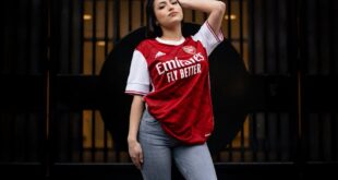 Young woman posing confidently in an Arsenal FC jersey. Urban background adds to the stylish look.