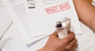 Man holding bills labeled 'Past Due' and a drink can, lying on a sofa.