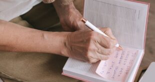 Close-up of a woman writing in a journal with a pen, capturing personal thoughts indoors.
