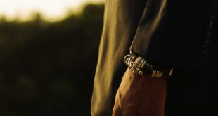 A close-up of a man's hand adorned with rings and bracelet, captured outdoors in Ghana.