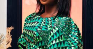 Elegant studio portrait of a woman in a vibrant green geometric top against a warm pink and blue backdrop.