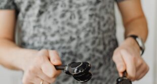 Close-up image of a man playing castanets indoors, focusing on the hands and instruments.