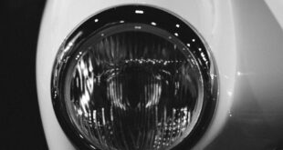 Elegant close-up of a vintage car headlight in grayscale, capturing timeless design.