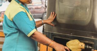 Indian woman refilling vehicle at urban gas station, demonstrating everyday life.