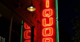 Bright neon liquor store sign glowing against the night sky.