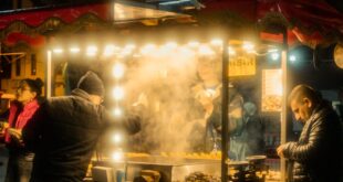 Candid street food stall scene at night in a vibrant city market, bustling with activity.