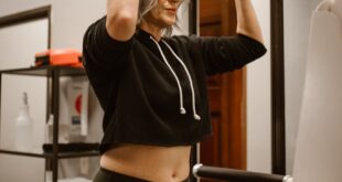 A determined woman in gym wear using a pull-up machine indoors.