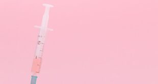 A syringe extracts liquid from a vial on a pink background, signifying medical treatment.