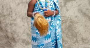 Portrait of a smiling child in blue traditional attire with accessories.
