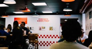 Diners enjoying their meals in a warmly lit Five Guys restaurant, embodying a friendly and inviting atmosphere.