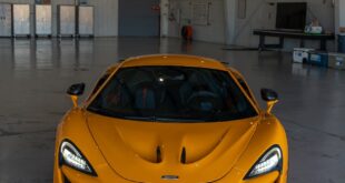 Vibrant yellow McLaren supercar showcased in an expansive industrial garage.