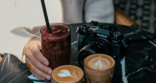 Stylish café table in İstanbul with coffees, smoothie, and camera on a black marble table.