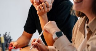 Two young adults smiling and collaborating using a digital tablet with stylus.