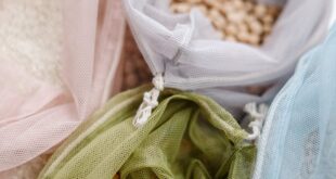 Assorted grains in colorful, reusable mesh bags on a white background.