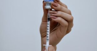 Hands holding a syringe and vial, preparing a Botox injection. Professional aesthetic procedure concept.