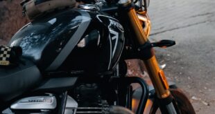 Close-up of a black motorcycle parked outdoors under a tree in Bengaluru, showcasing classic design and urban adventure.
