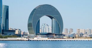 Scenic view of Baku's distinctive ring-shaped building by the water.