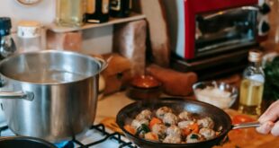 A cozy kitchen setting with meatballs frying on the stove and sauce simmering nearby.