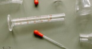 Scientific laboratory equipment with a molecular model on a green background.