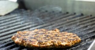 Close-up of a sizzling burger patty being cooked on an iron grill, perfect for BBQ lovers.