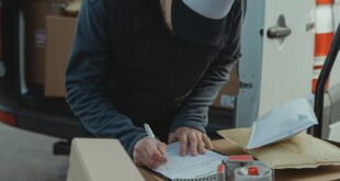 Courier organizing packages from a van, preparing for delivery in a logistics setting.