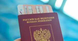Russian passport held in hand with boarding pass peeking out, ready for travel.