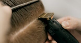 Close-up of a barber using clippers and comb to trim a client's hair at a salon.