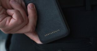 Close-up of a man holding a smartphone with a luxury case indoors.