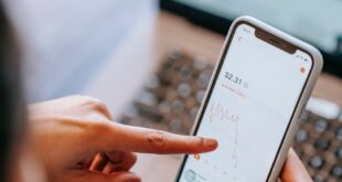 Close-up of hands using smartphone to analyze stock market data.