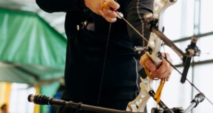 A male archer aiming with concentration during an indoor practice session, showcasing precision and focus.