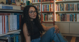 Young woman sitting in a library surrounded by books, enjoying a quiet reading moment.