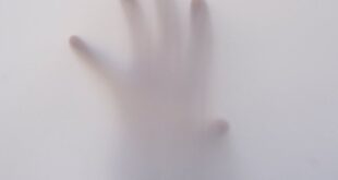 Eerie image of a hand reaching through a foggy surface, evoking mystery and suspense.