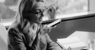 Black and white photo of a woman using voice commands in an office setting.
