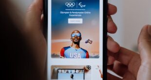 Person holding a smartphone showing Olympic and Paralympic online experiences.